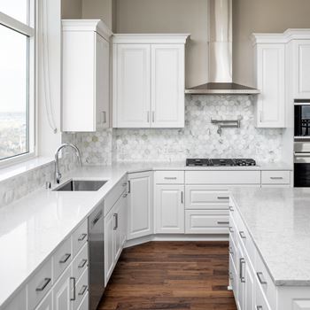 A white kitchen with marble counter tops and white cabinets